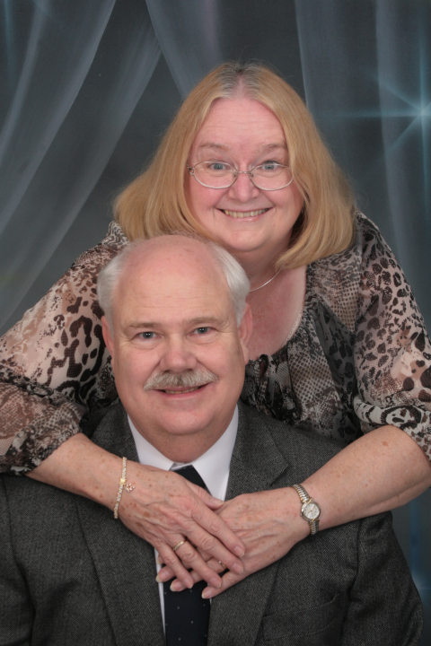 A portrait of John and Gay. John is seated and Gay is standing.